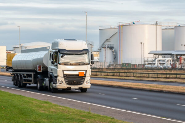 Tanker truck in motion on the road with oil depot in the background